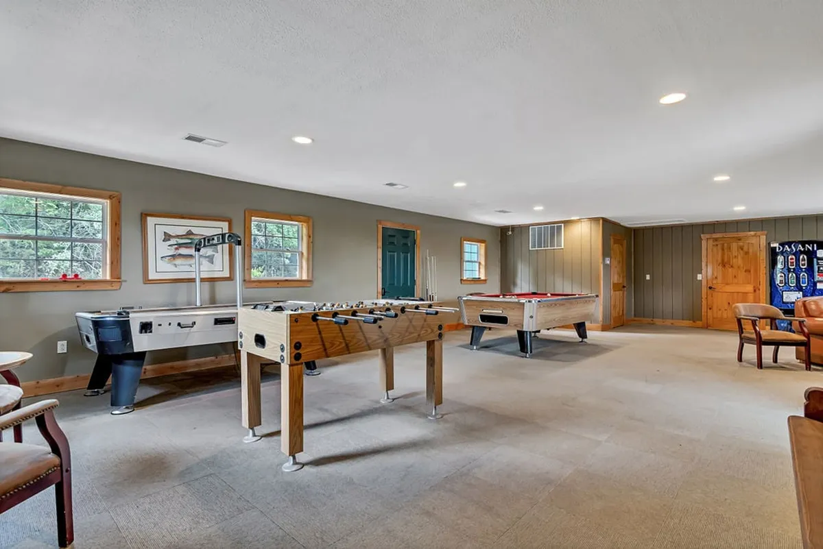 An inviting interior space featuring a foosball table, pool table, and a comfortable seating area in the lower-level family room. The room radiates a fun and relaxed vibe, perfect for movie nights, games, or cooling off after hot tub sessions.
