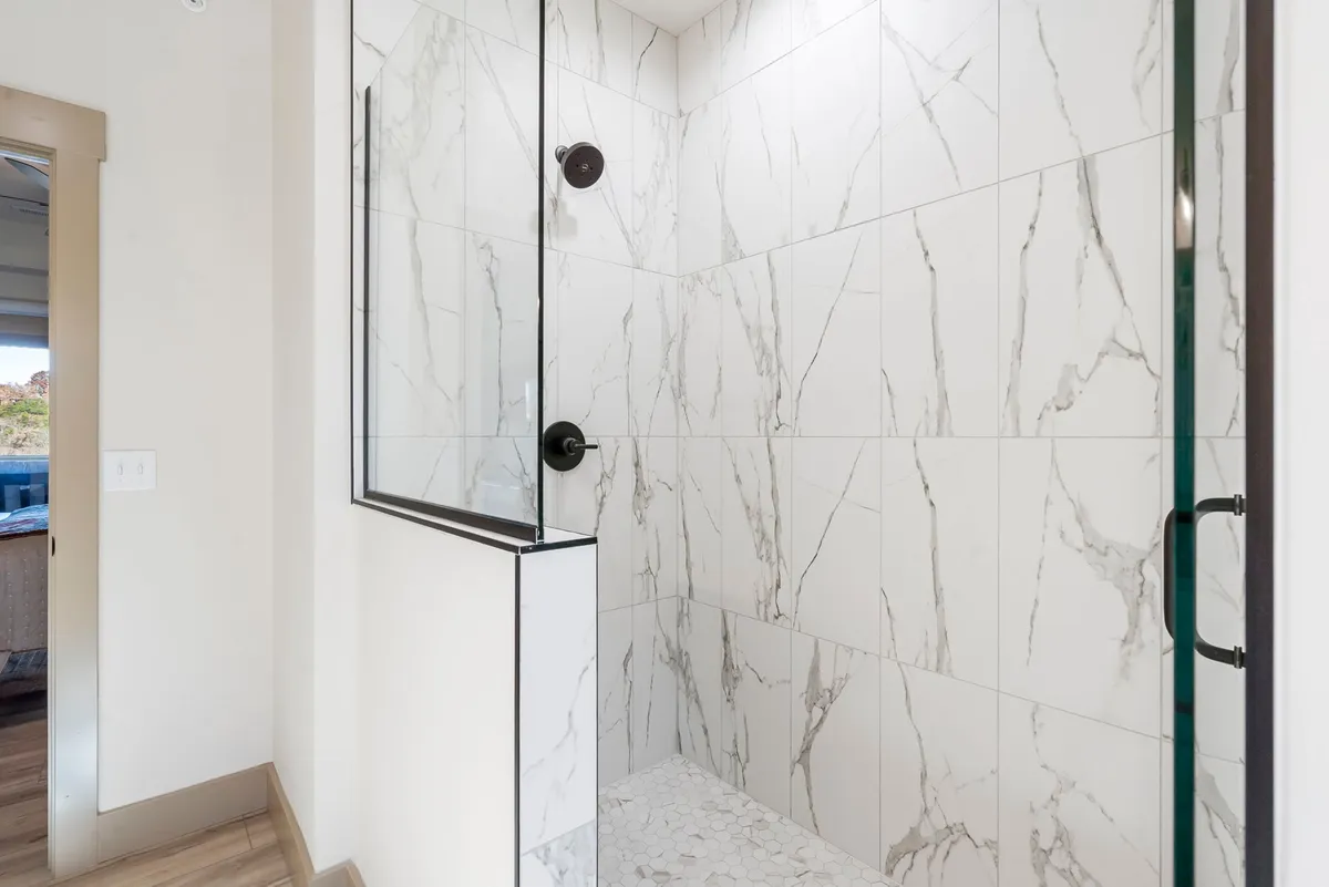 A luxurious bathroom featuring a glass shower enclosure, marble tiles, and modern black fixtures. The space exudes calm and invites guests to rejuvenate after a day’s adventure.