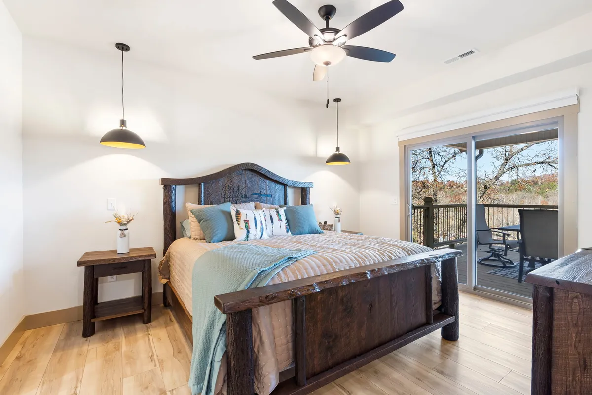 A peaceful bedroom with a large wooden bed, sliding glass door, and nature views just beyond. Soft lighting and simple decor evoke quiet mornings and restful nights.