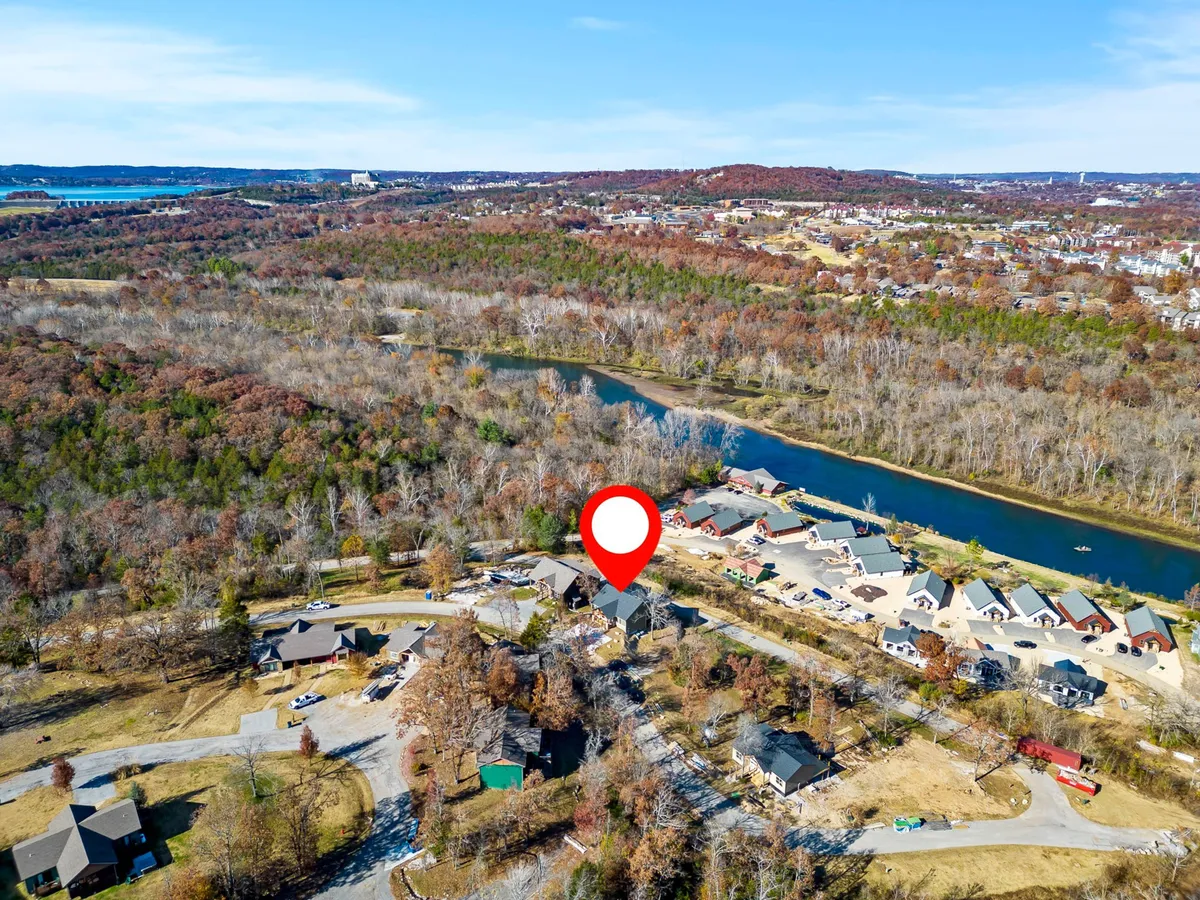This image captures a tranquil river bordered by vibrant autumn foliage, residential homes, and gently curving roadways. The view invites thoughts of fishing, walking, and biking along the scenic waterfront, perfectly embodying an active yet peaceful outdoor lifestyle.