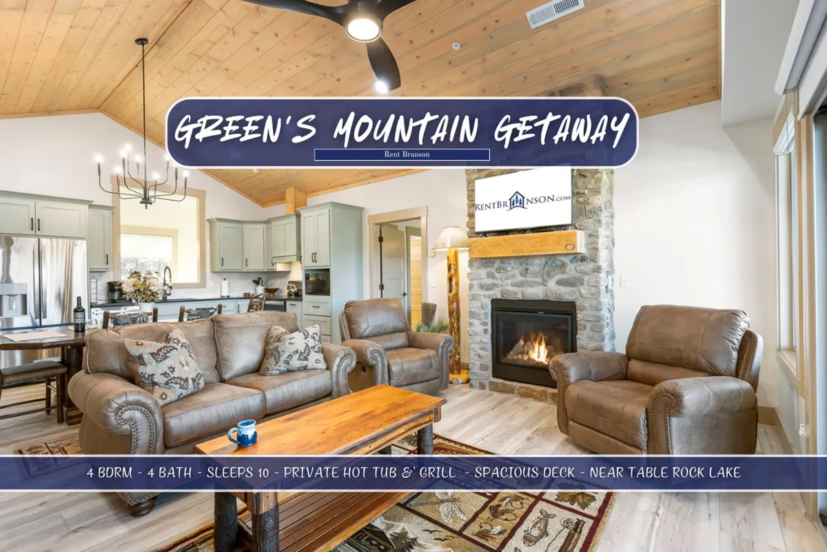A living space with a stone fireplace as the focal point, plush seating arranged for conversation or relaxation, and a view extending into the kitchen area with exposed wooden beams above. The lighting is warm and welcoming, ideal for evenings around the fire or movie nights.