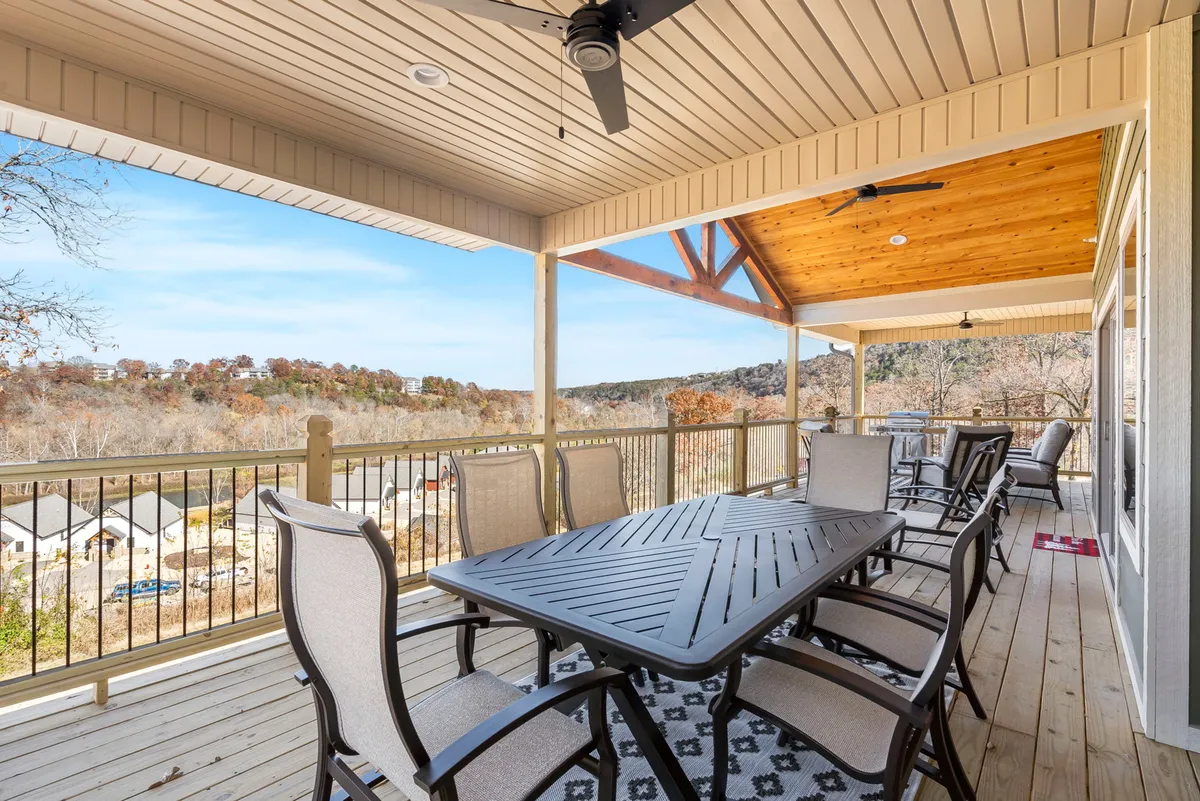 An exterior view of an outdoor dining table under a roof structure, surrounded by a picturesque landscape. The scene suggests opportunities for social gatherings, outdoor dining, and relaxation with scenic views.