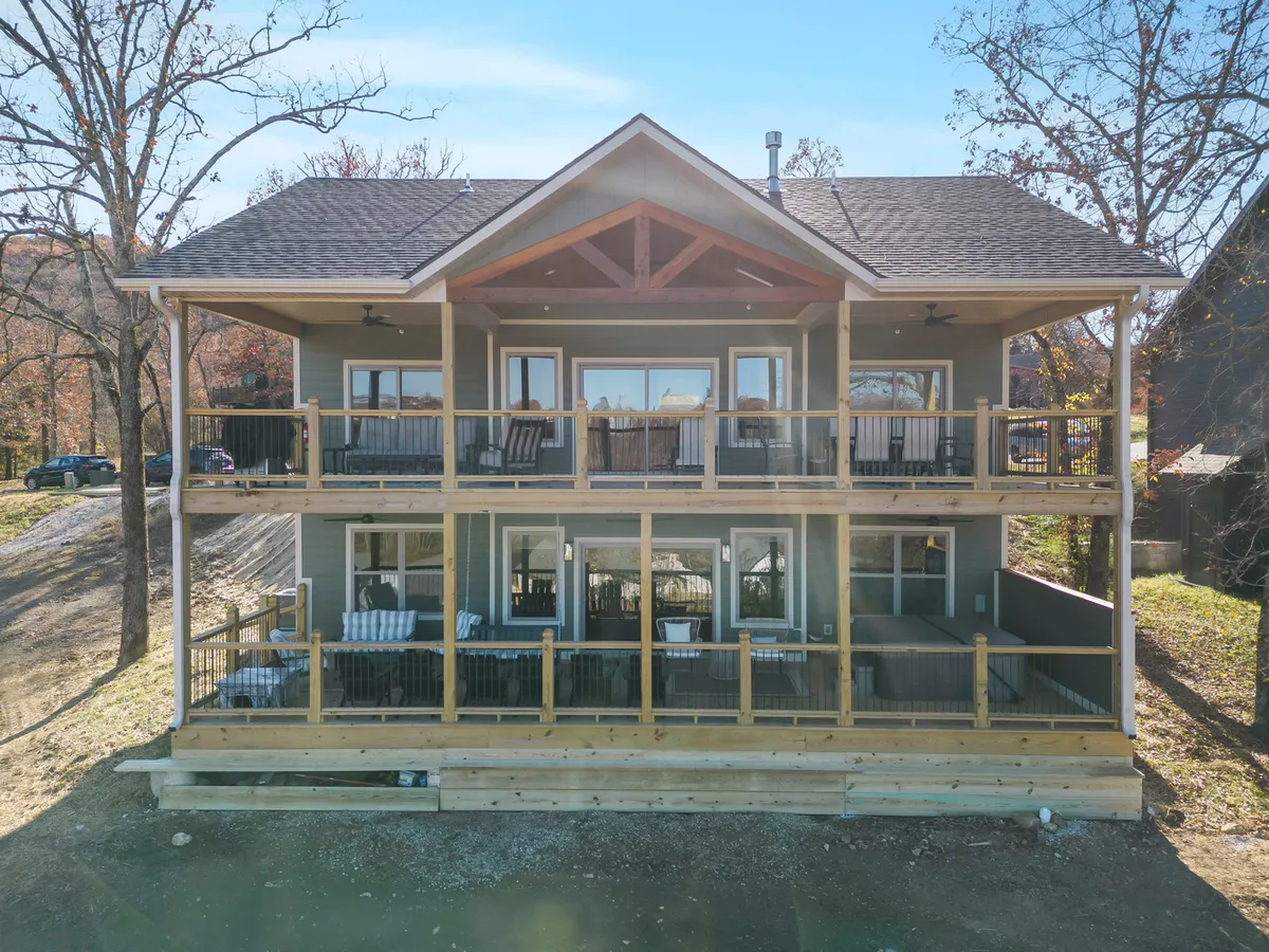 A large, wooden balcony with surrounding landscaping provides a picturesque setting for morning coffee or sunset relaxation. The design encourages group conversations and offers a strong connection to nature, enhancing the sense of retreat.